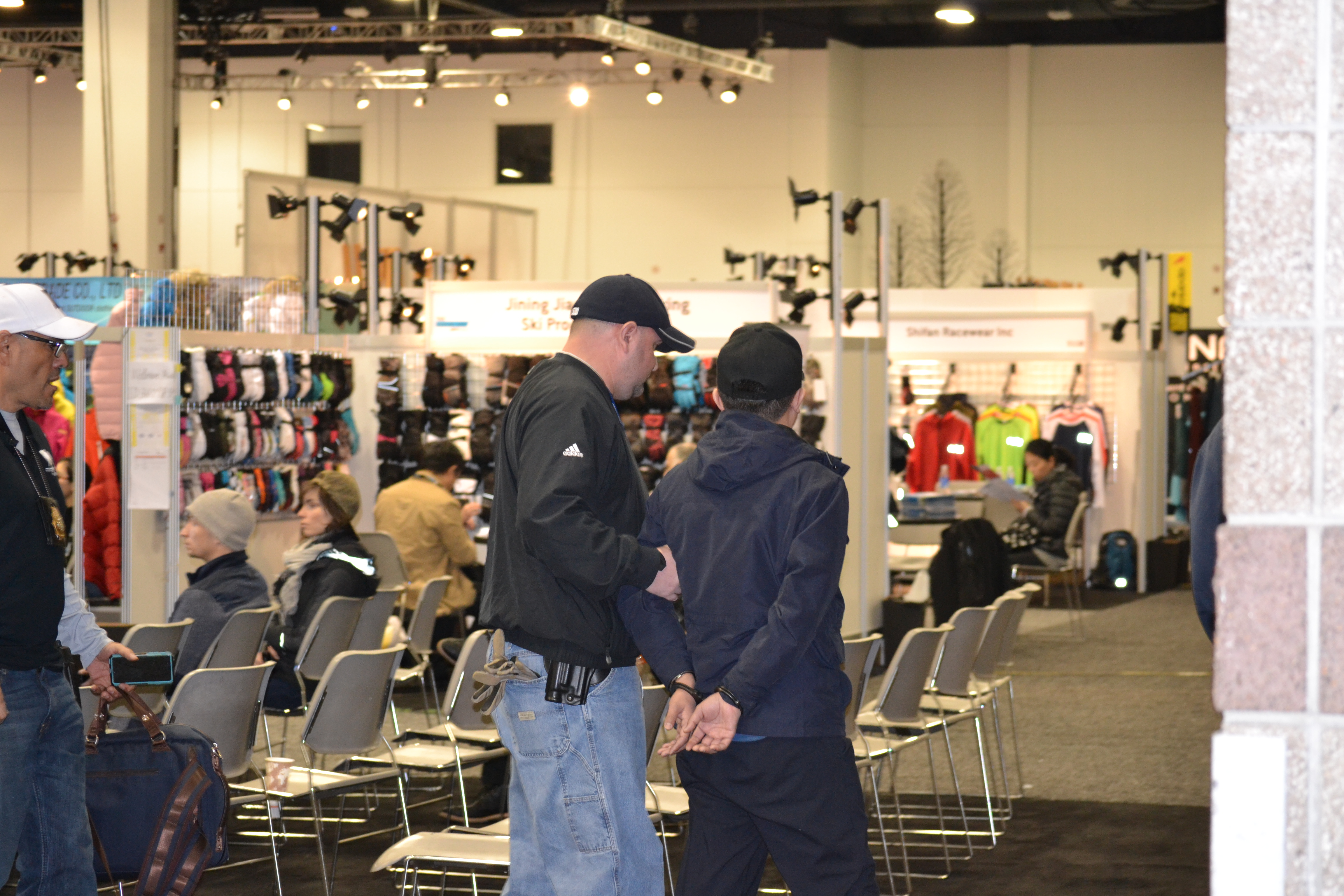 Guangzhou Botai U.S. representative and co-owner, Daniel Gong, being taken into custody on the showroom floor at the SIA Snow Show in Denver, CO.